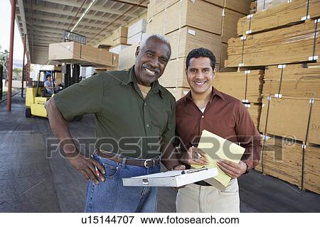 Warehouse Workers in front of man working with forklift View Large Photo Image Stock Photo - Warehouse Workers in front of man working with forklift. Fotosearch