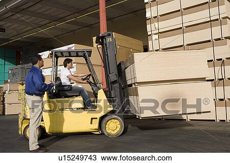 Stock Image - Warehouseman and forklift truck driver. Fotosearch