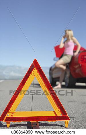 Warning triangle in front of woman on cell phone by red sports car View Large Photo Image Stock Image - Warning triangle in front of woman on cell phone by red sports car. Fotosearch