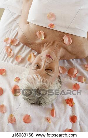 Stock Photo - Woman at spa with rose petals around, head and shoulders. Fotosearch