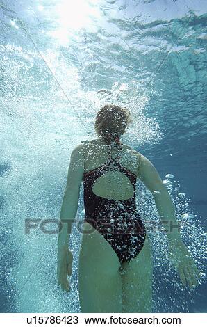 Stock Image - Woman coming up for air in pool, back view. Fotosearch