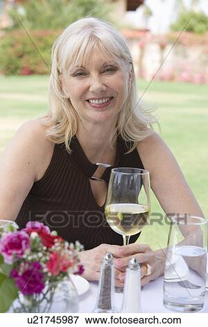 Stock Photo - Woman drinking wine outdoors, portrait. Fotosearch