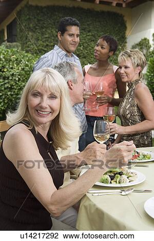 Stock Image - Woman drinking wine with friends outdoors. Fotosearch