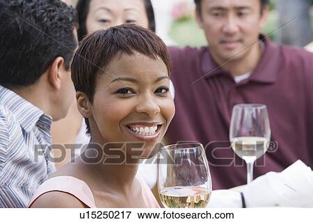 Stock Photo - Woman drinking wine with friends outdoors. Fotosearch