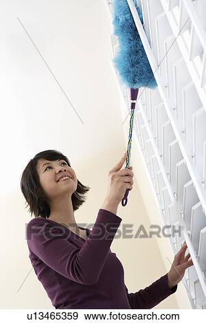 Stock Photo - Woman dusting, low angle view. Fotosearch
