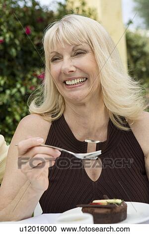 Stock Image - Woman eating dessert outdoors. Fotosearch