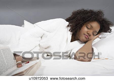 Woman holding book sleeping on bed View Large Photo Image Stock Image - Woman holding book sleeping on bed. Fotosearch