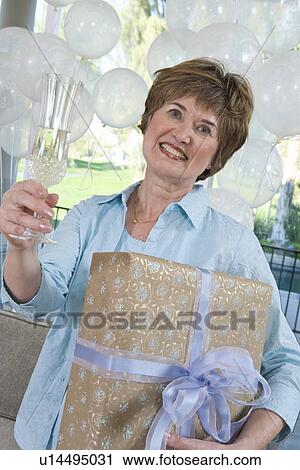Woman holding gift and glass of champagne at party View Large Photo Image Stock Image - Woman holding gift and glass of champagne at party. Fotosearch