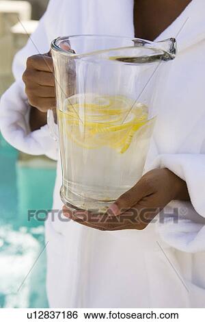 Stock Photograph - Woman holding jug of water, close-up. Fotosearch
