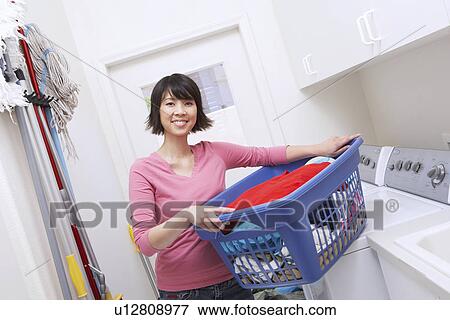 Stock Photo - Woman holding laundry basket, portrait. Fotosearch