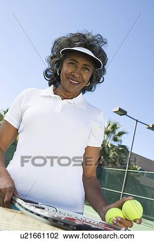 Stock Image - Woman holding tennis racket, portrait. Fotosearch