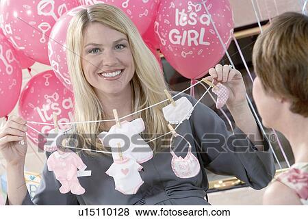 Stock Photo - Woman holding up gift at baby shower. Fotosearch