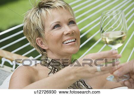 Woman holding wine in hammock View Large Photo Image Stock Image - Woman holding wine in hammock. Fotosearch