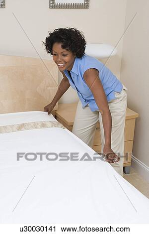 Stock Image - Woman making a bed. Fotosearch