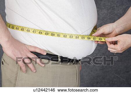 Woman measuring waist of overweight man with tape measure, middle section View Large Photo Image Stock Photograph - Woman measuring waist of overweight man with tape measure, middle section. Fotosearch