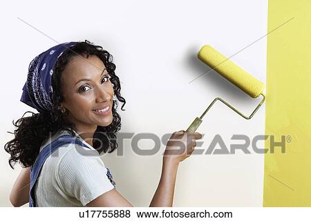Stock Photo - Woman painting wall yellow, portrait. Fotosearch