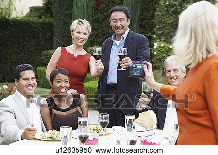 Woman photographing friends celebrating with food and drink in garden View Large Photo Image Stock Image - Woman photographing friends celebrating with food and drink in garden. Fotosearch