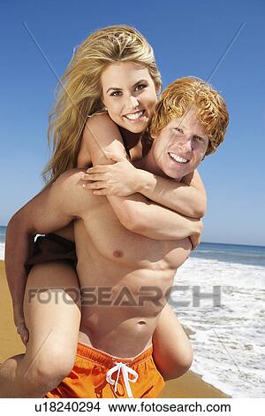Woman riding on man's back on beach View Large Photo Image Picture - Woman riding on man's back on beach. Fotosearch