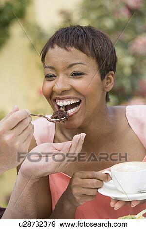 Stock Photo - Woman sharing dessert outdoors. Fotosearch