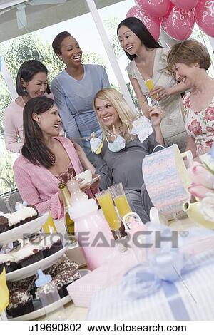 Stock Image - Woman showing off gift at baby shower. Fotosearch