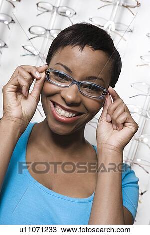 Stock Image - Woman trying on eyeglasses in store. Fotosearch