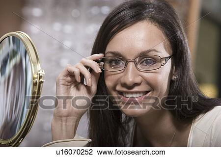 Stock Image - Woman trying on eyeglasses in store. Fotosearch