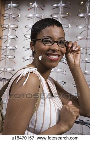 Stock Photo - Woman trying on eyeglasses in store. Fotosearch