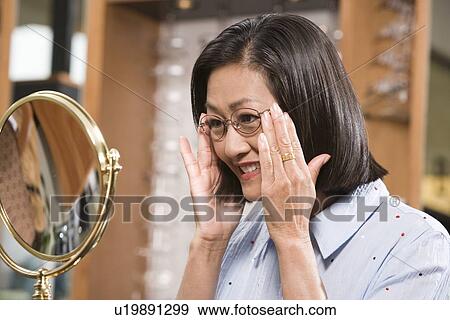 Woman trying on eyeglasses in store View Large Photo Image Stock Photo - Woman trying on eyeglasses in store. Fotosearch