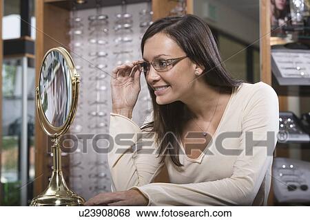 Stock Photo - Woman trying on eyeglasses in store. Fotosearch