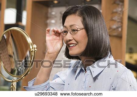 Stock Photo - Woman trying on eyeglasses in store. Fotosearch