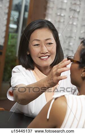 Woman trying on glasses with optician View Large Photo Image Stock Photo - Woman trying on glasses with optician. Fotosearch