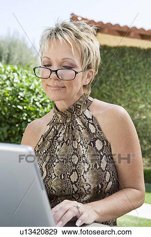 Stock Photo - Woman using laptop in back yard. Fotosearch