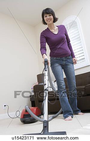 Woman vacuuming floor in living room View Large Photo Image Stock Image - Woman vacuuming floor in living room. Fotosearch