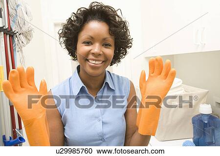 Stock Image - Woman wearing washing up gloves. Fotosearch