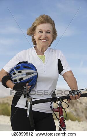 Stock Image - Woman with bicycle and helmet, portrait. Fotosearch