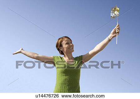 Stock Photograph - Woman with pinwheel, portrait, low angle view. Fotosearch