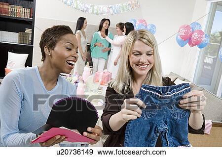 Stock Photo - Women at a Baby Shower with baby Clothes. Fotosearch