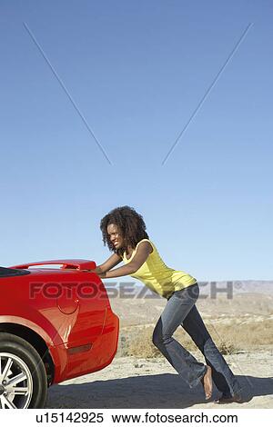 Women pushing broken down sports car on desert road View Large Photo Image Stock Photography - Women pushing broken down sports car on desert road. Fotosearch
