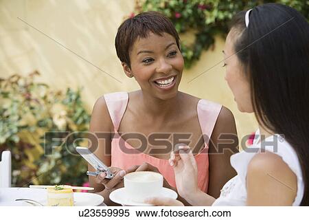 Stock Photography - Women talking at outdoor table. Fotosearch