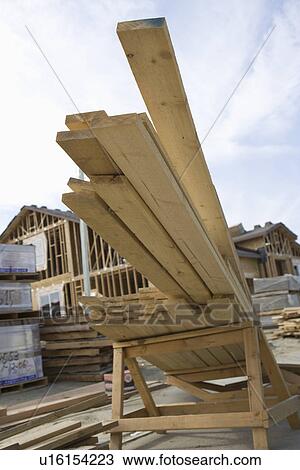 Stock Image - Wooden planks on pile on construction site. Fotosearch