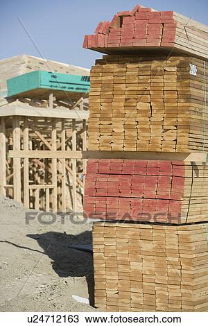 Stock Image - Wooden planks stacked on construction site. Fotosearch