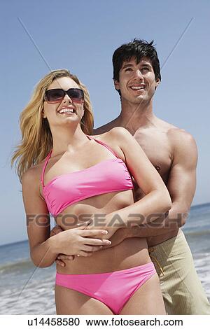 Young couple embracing on beach, low angle view View Large Photo Image Stock Image - Young couple embracing on beach, low angle view. Fotosearch