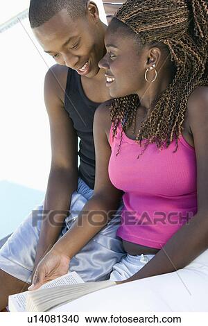 Stock Image - Young Couple Reading a Book. Fotosearch