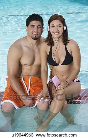 Stock Image - Young Couple Relaxing in Swimming Pool, Portrait. Fotosearch