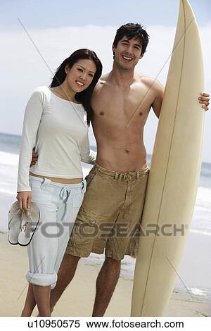 Stock Photography - Young couple with surfboard on beach. Fotosearch
