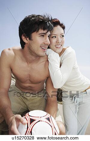 Stock Photo - Young couple with Volleyball on beach. Fotosearch