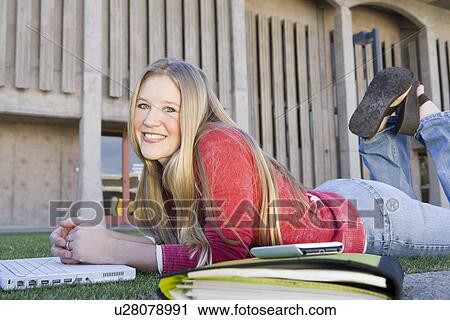 Young female student lying on front on grass during class break View Large Photo Image Stock Image - Young female student lying on front on grass during class break. Fotosearch