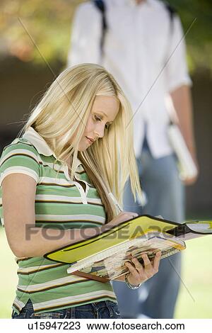 Stock Image - Young female student writing in notebook. Fotosearch