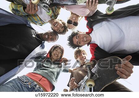 Stock Image - Young friends in huddle, view from below. Fotosearch
