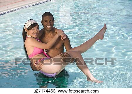 Young Man Carrying Young Woman in Swimming Pool, Portrait View Large Photo Image Stock Image - Young Man Carrying Young Woman in Swimming Pool, Portrait. Fotosearch
